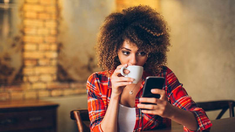 Woman drinking coffee on cell phone