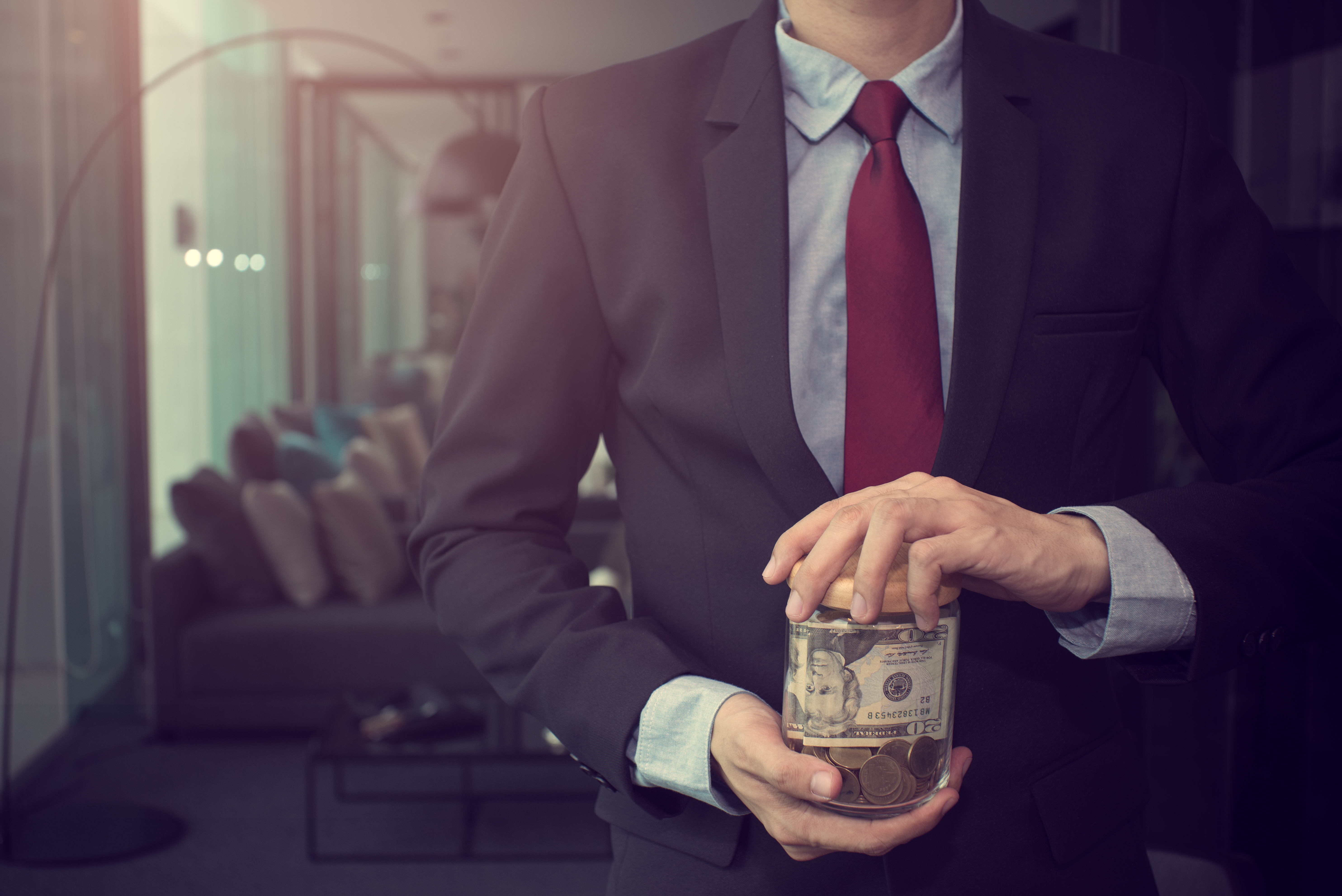 business man holding jar of cash